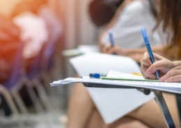 Exam at school with student's taking educational admission test in class, thinking hard, writing answer in university classroom, education and world literacy day concept