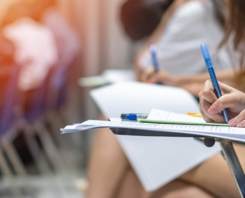 Exam at school with student's taking educational admission test in class, thinking hard, writing answer in university classroom, education and world literacy day concept