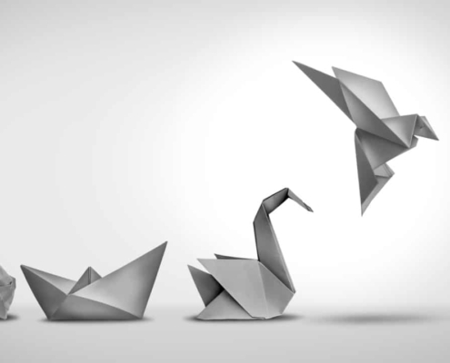 Changing for success as a leadership and business change through innovation and evolution of ability as a crumpled paper transforming into a boat then a swan and a flying bird as a metaphor.